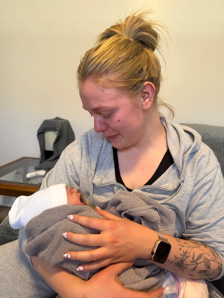 A postpartum doula cradling a newborn